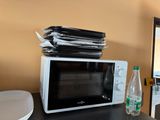 un micro-ondes sur lequel est posée une pile de papiers