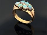 un gros plan d'une bague en or ornée d'oplites sur un fond noir