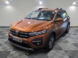 La voiture orange est garée sur un sol à damier dans le garage.