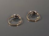 two gold rings with diamonds on a table