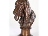une statue en bronze représentant un basset hound posée sur un socle