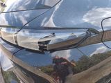 a reflection of a person taking a picture of a car