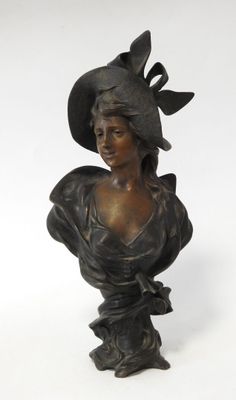 bronze bust of a woman wearing a hat and a dress