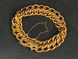 une image représentant un bracelet à chaîne en or muni d'un fermoir, sur fond noir