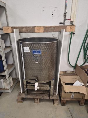 un grand réservoir métallique posé sur une palette dans un garage