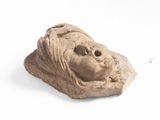 statue of a woman ' s head on a rock on a white surface