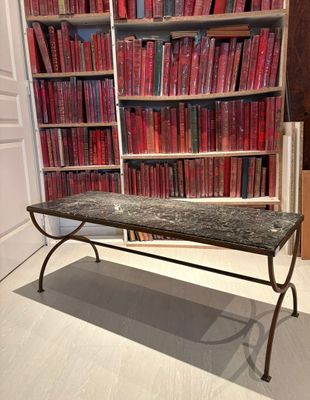 une table au plateau en marbre placée devant une bibliothèque