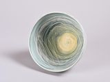 a white bowl with a green and yellow swirl inside of it