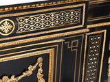 a black and gold cabinet with a mirror on top of it