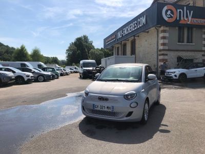 a small car parked in front of a building with a lot of cars parked in front of it