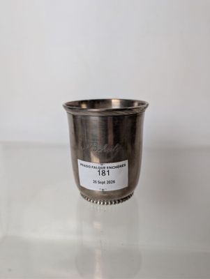 a silver cup sitting on top of a glass table next to a white wall