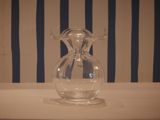 a glass vase sitting on a table with a striped wall behind it