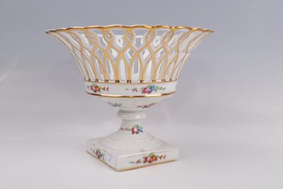 un vase blanc à bord doré, posé sur un socle