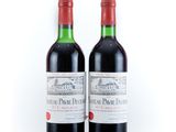 two bottles of red wine sitting next to each other on a white surface