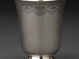 une coupe ancienne en argent posée sur un socle, sur fond noir