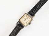 an old wrist watch with a black leather band and a gold face