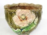 a green bowl with a flower on it on a white surface