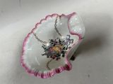 a pink and white bowl with a chain hanging from it