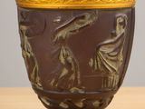 a brown vase with a gold rim sitting on a table