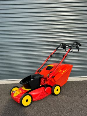 une tondeuse à gazon rouge garée devant la porte d'un garage