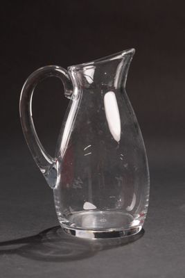 un pichet en verre posé sur une table, sur fond noir