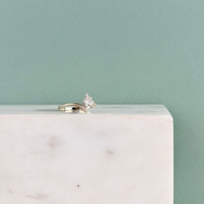 an engagement ring sitting on top of a white marble block