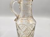a clear glass pitcher with a gold decoration on it