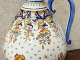 a vase with a blue handle sitting on a wooden table