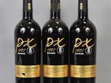 three bottles of red wine sitting on top of a glass table