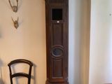 une horloge de parquet dans un coin de la pièce, à côté d'un fauteuil