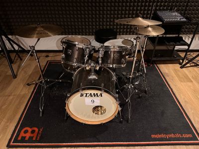 a drum set up on a mat in a recording studio