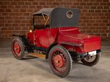 a red and black antique car parked in front of a brick wall