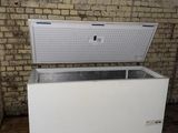 a white chest freezer sitting in front of a brick wall