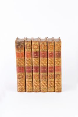 six old books are stacked on top of each other on a white surface