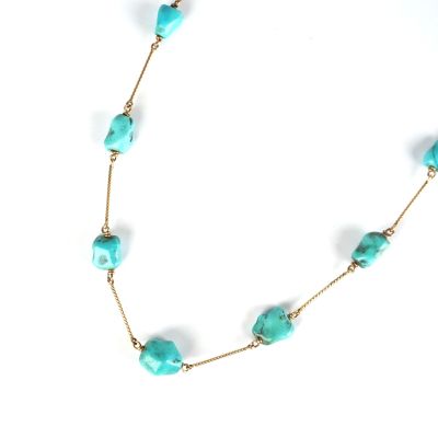 un gros plan d'un collier orné de perles de turquoise sur fond blanc