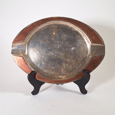 une assiette en argent posée sur un support en bois, sur un fond blanc