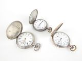 three silver pocket watches are sitting next to each other on a white surface