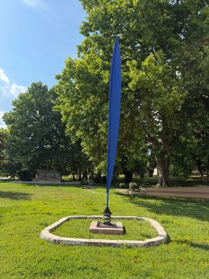 a blue sculpture in the middle of a grassy area