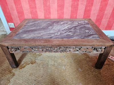 une table avec un plateau en marbre posée sur un sol recouvert de moquette