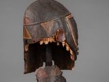 a close up of a wooden sculpture of a helmet on a stand