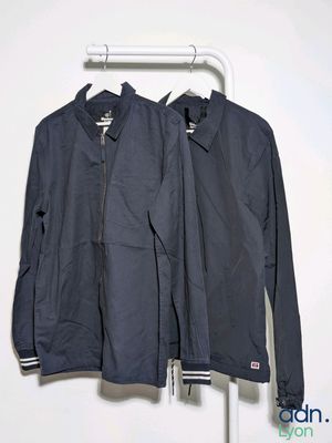 two jackets hanging on a clothes rack in front of a white wall