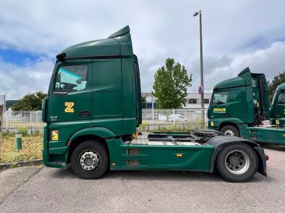 two green trucks parked next to each other in a parking lot