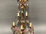 a close up of a chandelier with candles and flowers on it