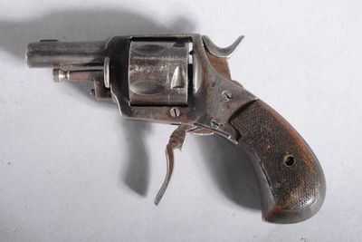 un vieux revolver avec une poignée en bois sur une surface blanche