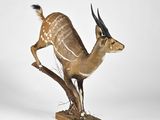 an antelope standing on its hind legs on a wooden base