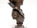 a bronze bust of a woman with a bow on a wooden base