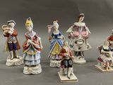 five figurines of people dressed in different outfits