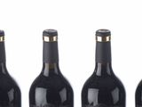six bottles of wine are lined up in a row on a white surface