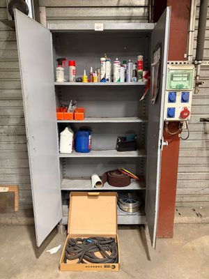 une armoire métallique contenant des outils, avec une boîte posée devant