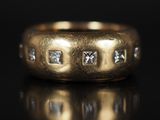 gros plan d'une bague en or avec des diamants sur une surface noire